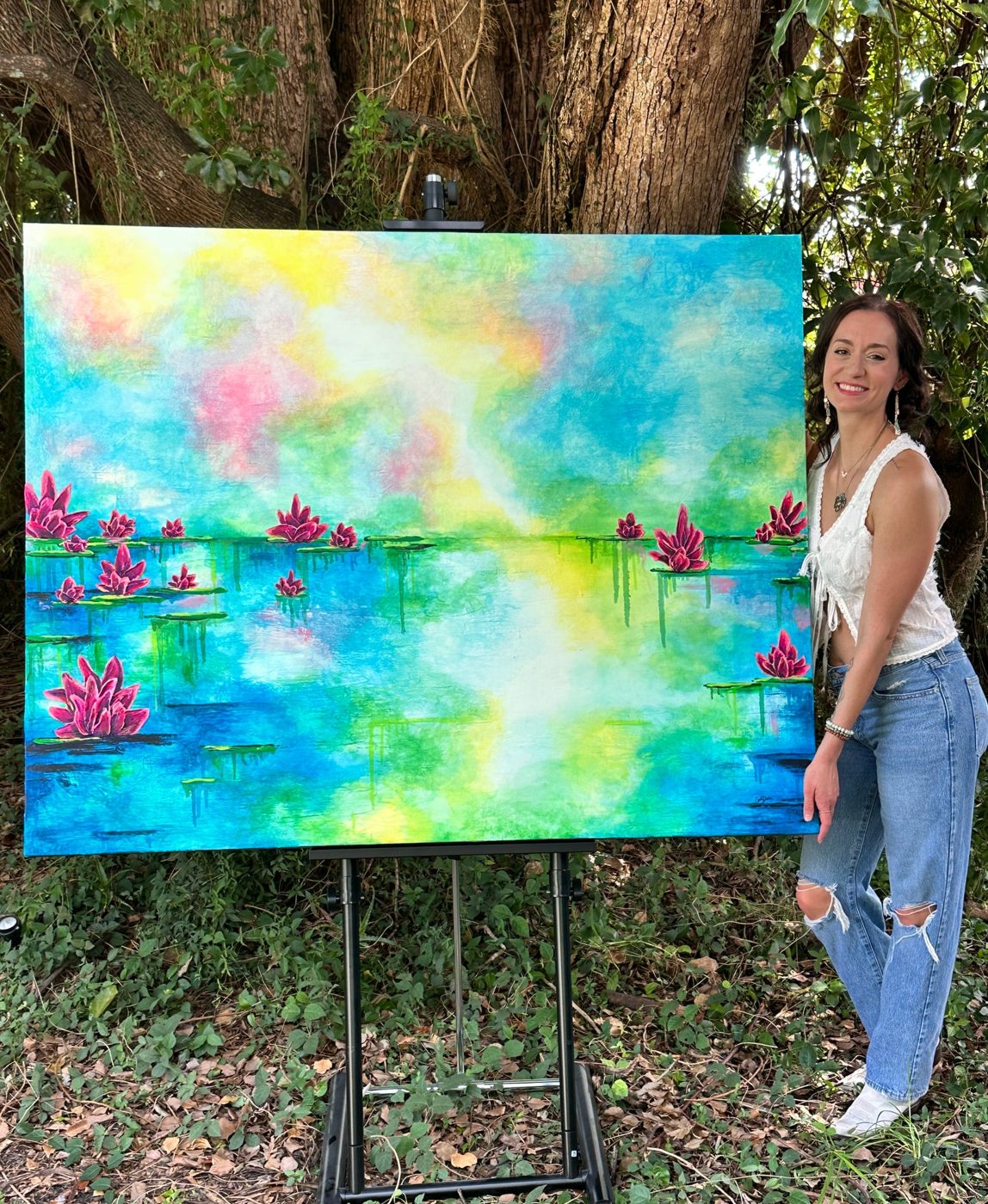 carli danae beside her water lily painting on an easel