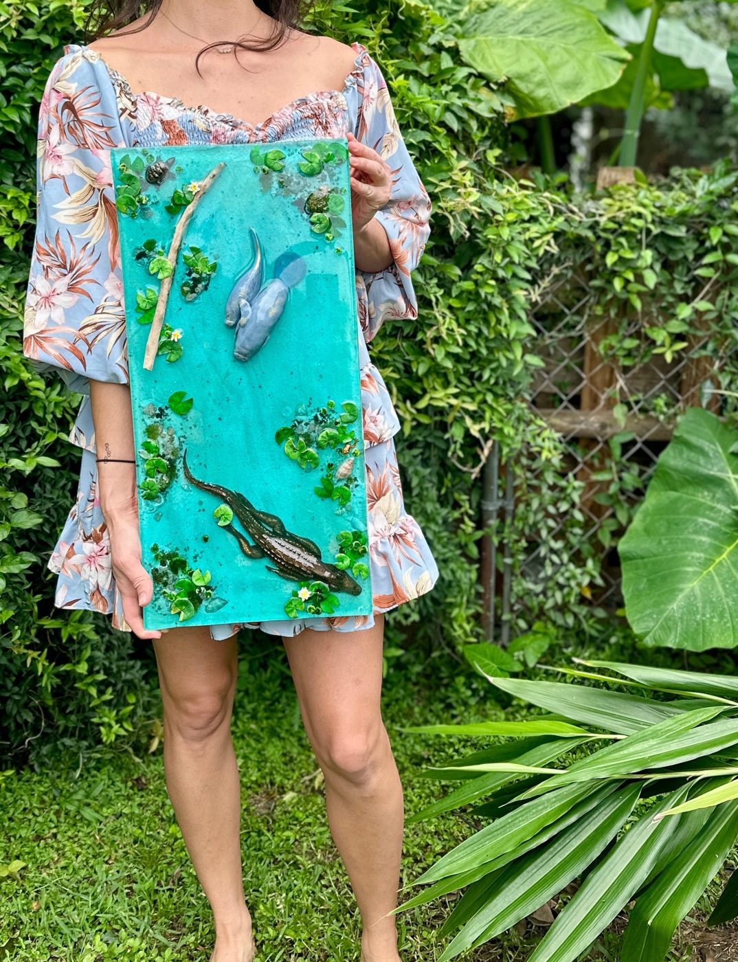carli danae holding a resin panel with manatees and an alligator